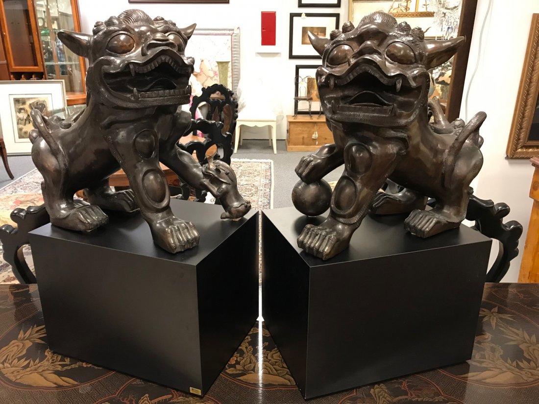 PAIR CHINESE LARGE BRONZE FOO DOGS: Pair of Chinese bronze foo dogs. Male and female with baby. Each statue sits on a black plinth base. Each dog measures 16.75" tall x 18" long and 13" wide, the bases are 16" long by 12" wide and the f