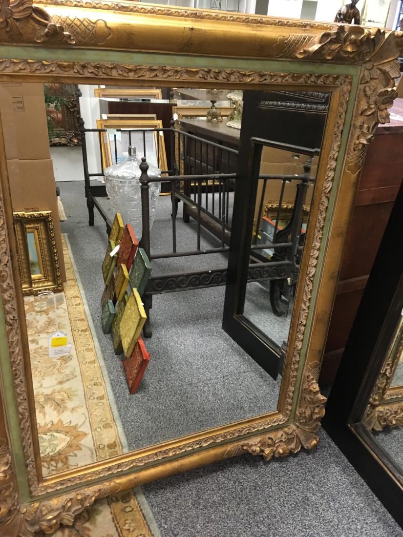 LARGE GILDED FLORAL DECORATED MIRROR: Large wood mirror with floral relief, light green faux painting, and beveled glass. Measures: 51" tall x 41" wide x 4" deep. Condition: good.