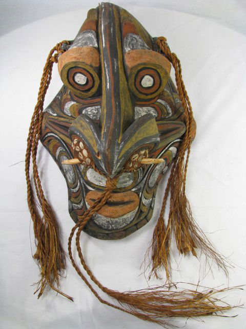 CARVED PAINTED SEPIK RIVER WOOD MASK w/ SHELLS: Large primitive carved and painted wood mask accented with straw braids and shells, Sepik River area in Papua New Guinea. Measures 18 1/4" high by 11 1/2" wide by 6" deep. 1/4" chip on nose.