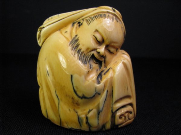 JAPANESE MAMMOTH IVORY OKIMONO SIGNED: Japanese carved ancient mammoth (elephant) ivory Okimono figurine of a man sitting down and resting his head on his knees. Signed on base. Measures 2 1/4" tall by 2" wide by 1 3/4" deep. Condition goo