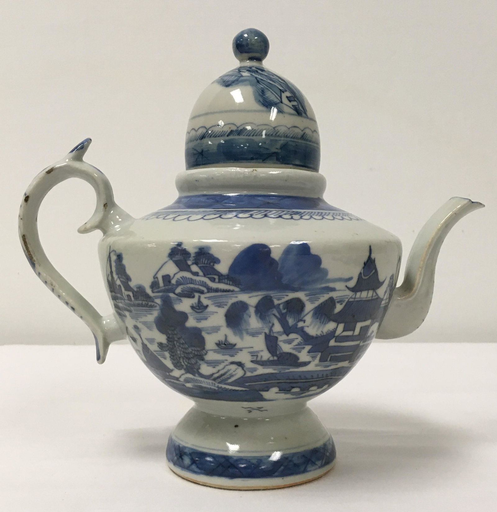 CHINESE QING DYNASTY CANTON BLUE & WHITE TEAPOT: Chinese Qing Dynasty Canton export blue and white porcelain teapot. Measures 8.5" tall x 9" wide (handle to spout). Unmarked. Condition: some minor fritting to handle edge, small chip to handle, a few