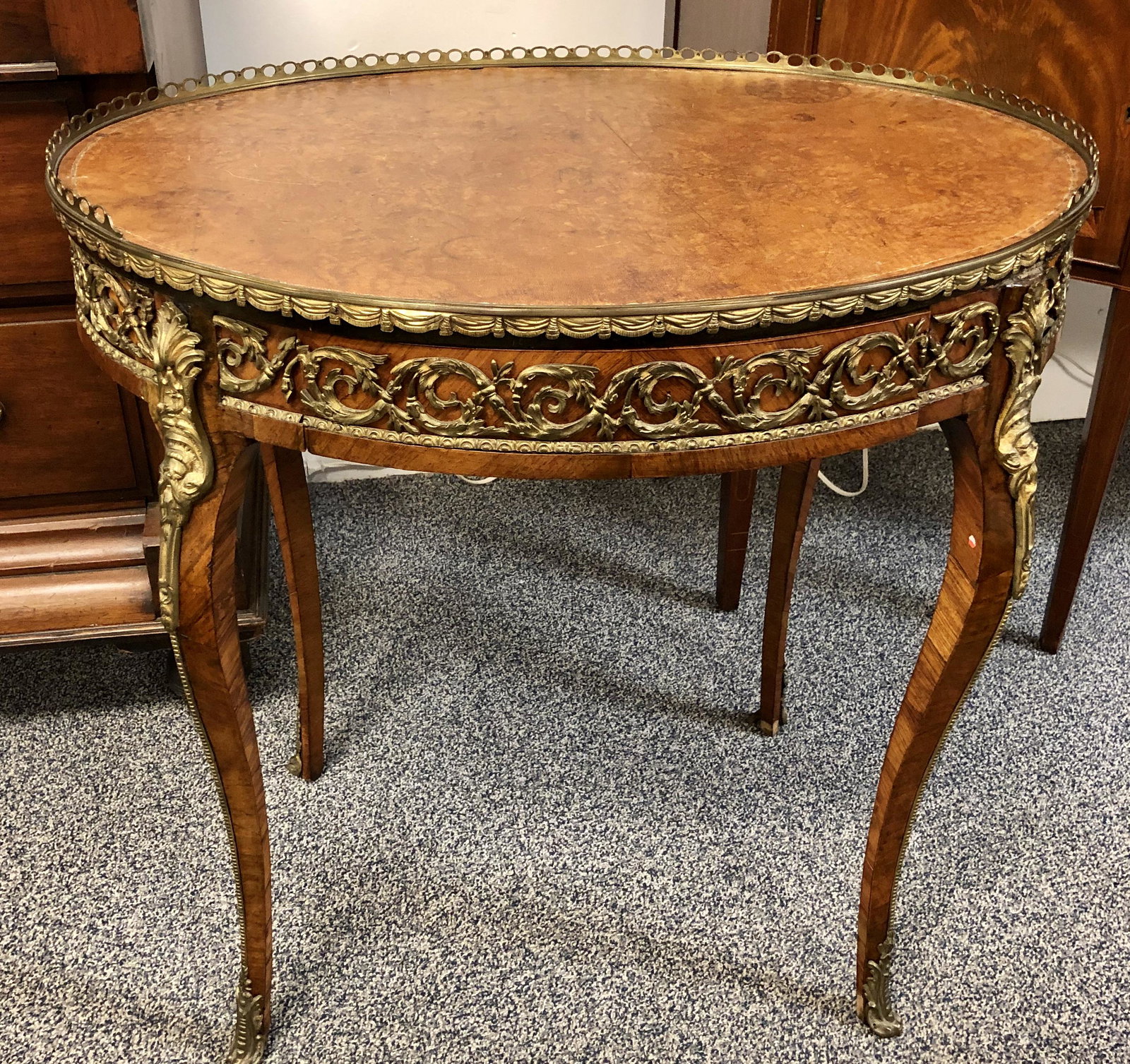 ANTIQUE ROCOCO STYLE ORMOLU MOUNTED SIDE TABLE: Antique Rococo style oval ormolu mounted side table with leather top. Bronze gallery around table edge, various ormolu mounts. Measures 29.5" long x 30" tall and 22.5" wide. Condition: ormolu intact, 