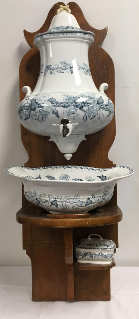 SARREGUEMINES PAVOT PORCELAIN LAVABO WASH SET: Sarreguemines "Pavot" transferware porcelain lavabo wash set with wooden shelf. Includes reservoir, bowl/basin, and a small covered soap dish. Condition: small covered dish is cracked and repaired, re