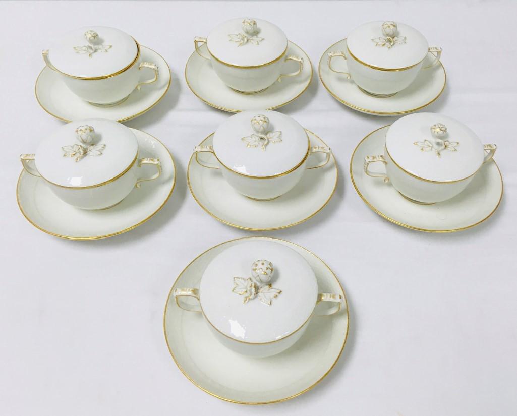 SEVEN KPM GERMAN PORCELAIN COVERED BOUILLON CUPS: Lot of seven KPM German porcelain embossed basket pattern covered bouillon cups and saucers. Gilt details, rose form finial. Marked on base. Cups each measure 5.75" wide handle to handle x 3.5" tall t