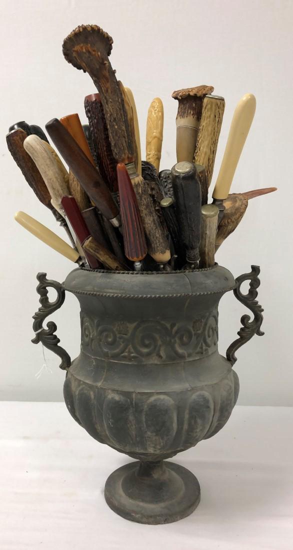 ANTIQUE HORN HANDLED CUTLERY CENTERPIECE: Antique horn handled cutlery centerpiece. Comprised of approximately 50 pieces of various cutlery, most with bone or horn handles, all in a metal-ware planter centerpiece. Whole assembly measures appr