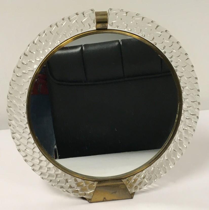 VINTAGE VENINI MURANO TWISTED GLASS VANITY MIRROR: Vintage Venini Italian Murano twisted glass vanity mirror measuring 13.25" in diameter. Brass frame and foot. Condition: minor tarnishing to brass ring around mirror panel, see images. Weight: 8 lbs.