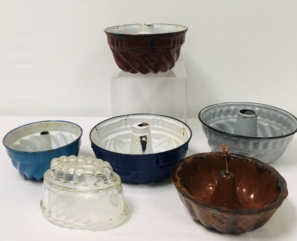 ASSORTED ANTIQUE BUNDT CAKE & JELLO MOLDS: Lot of assorted antique bundt cake and jello / gelatin molds. Includes one jello mold (glass), one pottery cake mold, and four enameled metal molds. Largest measures 10" in diameter. Condition: tiny f
