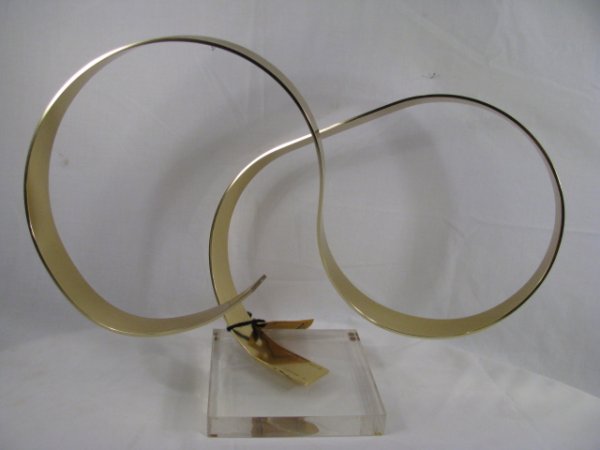 ABSTRACT BRASS SCULPTURE "A WOMEN" DAN MURPHY 1978: Modern polished brass sculpture by Dan Murphy, mounted on a square lucite base. Signed and titled "A Women" dated 1978. Measures 14" high by 19 3/4" wide by 8" deep. Minor surface wear. See images.