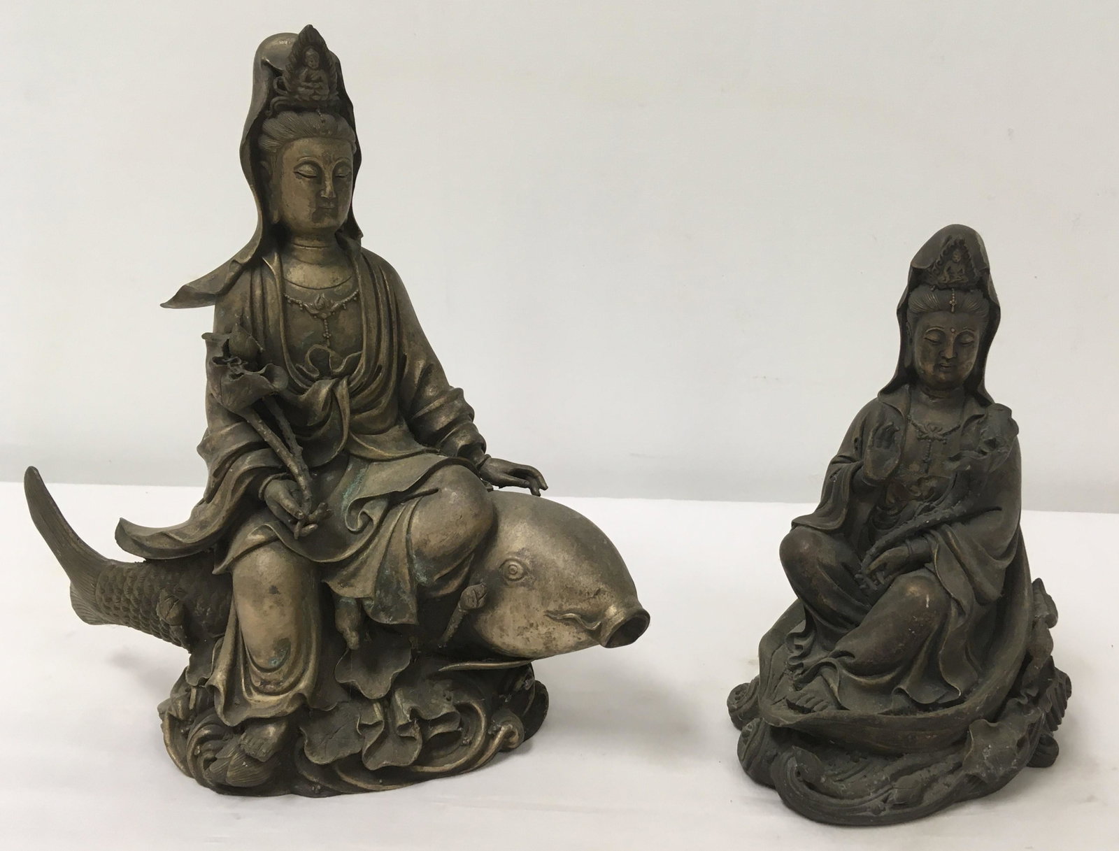 TWO CHINESE CAST WHITE METAL GUAN YIN SCULPTURES: Lot of two Chinese cast white metal sculptures of Guan Yin. Taller one measures 10.75" tall x approx. 10.5" long. Unsigned. Condition: signs of age and wear to finish, no repairs/losses, see images. W