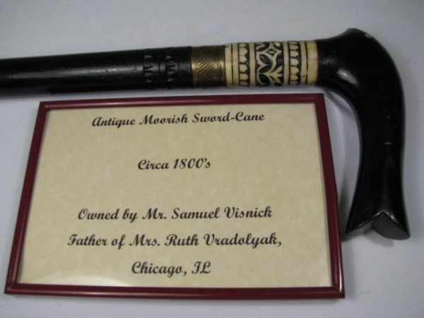 ANTIQUE MOORISH SWORD CANE 19TH C: Antique 19th century Moorish ebony sword cane with carved ivory and brass accents on the tip and shaft. No maker marks on sword. 26 is incised on the cane. Included with the cane is a small framed car