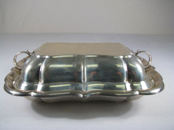 CARTIER STERLING SILVER COVERED CASSEROLE: Cartier sterling silver covered serving dish with two scrolled handles. Stamped : Cartier, Sterling, X959, Windsor. Weighs 32 troy ounces. Measures with lid 3 3/4" high by 11 1/2" long by 8 1/2" wide.