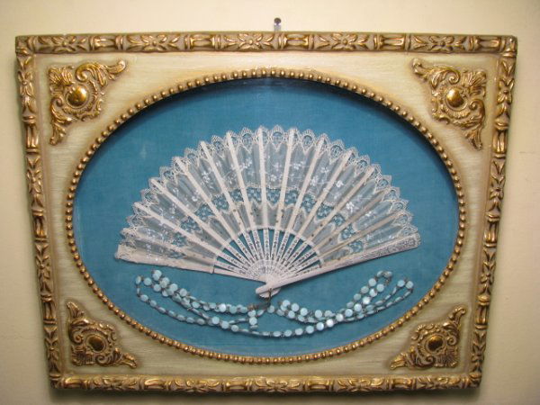 SHADOW BOX FRAMED ANTIQUE LACE FAN w BEADS: Antique lace fan with turquoise color beads set into a shadow box frame that has glass and a light blue velvet background. White lace fan is in an open position measures 7" tall by 12 1/2" wide. Gilt
