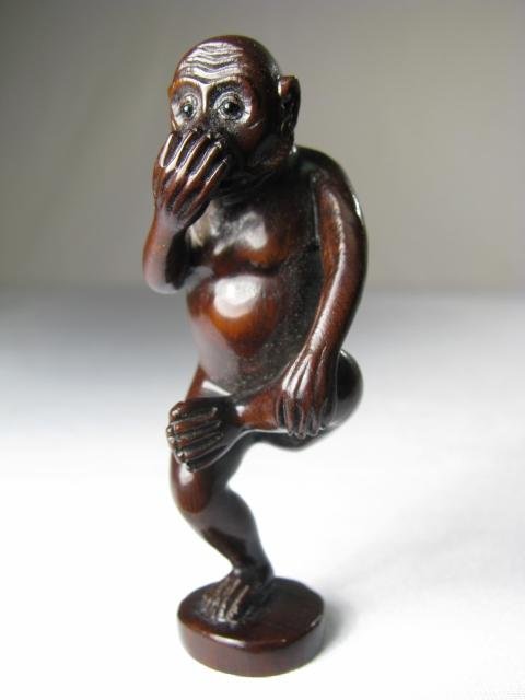 JAPANESE CARVED BOXWOOD NETSUKE: MONKEY HOPPING: A carved boxwood netsuke depicting a monkey hopping on one leg while holding the knee of the other leg and covering his mouth. Signed on the base. Measures 2 3/4" tall.
