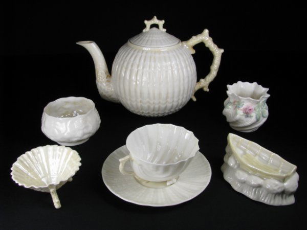 ASST BELLEEK PORCELAIN SHELL PATTERN 7 PCS: Green, brown and black marks. Teapot measures 7" tall x 10" wide, chip on inside lip, sugar bowl is 2 1/2" tall x 4" wide, saucer is 5 1/2" wide, cup is 2" tall x 4" wide, boat dish is 2" tall x 4 1/2