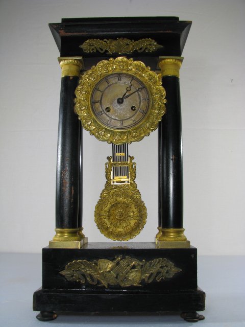 ANTIQUE FRENCH PORTICO CLOCK GILT ORMOLU TRIM: 19th century French clock with ebonized wood case, ornate gilt bronze mounts, time and strike mechanism. Working. Has pendulum, no key. Measures 10 1/2" long x 5 3/4" wide x 20" tall. A fair amount of