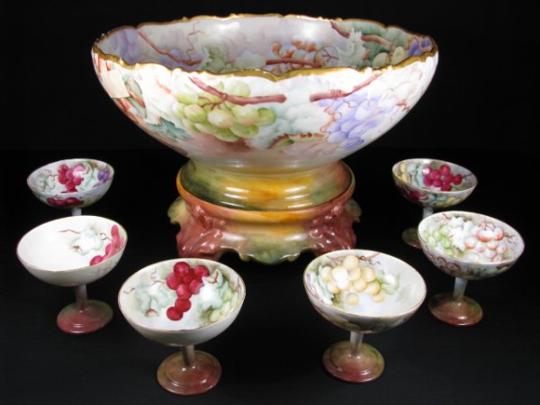ANTIQUE LIMOGES FRUIT OR PUNCH BOWL ON STAND 6 CUP: Hand painted Limoges porcelain. Marks on bottom. Artist signed in center of large bowl. Repair on lower rim of base and small repair to rim of one cup. Large bowl on stand measures 9 1/2" tall x 14" w