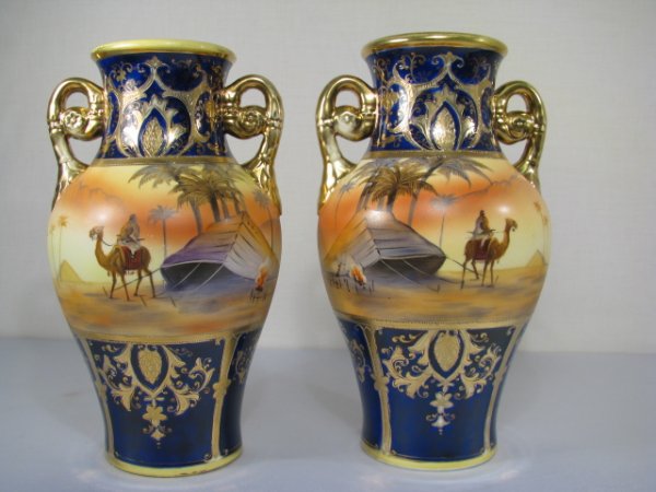 PAIR NORITAKE ORIENTALIST HAND PAINTED VASES: Pair of Noritake vases with hand painted orientalist desert scenes and gold gilt upon cobalt blue bands. No cracks, chips, or abrasions however there is wearing on select gold gilt accents. Measures 1