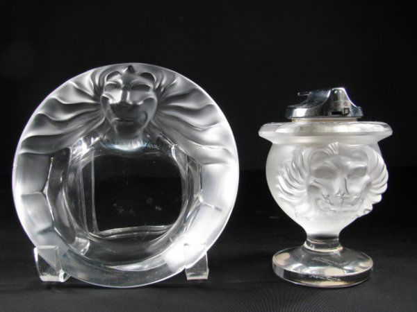 LALIQUE CRYSTAL CIGAR ASHTRAY & LIGHTER TETE DE LI: Both signed, Lalique France. Table lighter measures 5" tall x 3 1/2" wide with ash tray at 1 1/2" tall x 6" wide. Slight scratches on bases and minor chip to rim of ashtray. Total weight is 3 lbs 4 oz