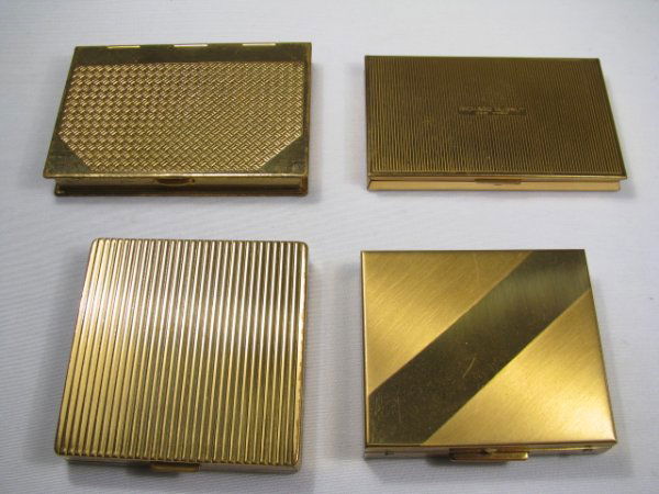 FOUR ASSORTED GOLD TONED METAL COMPACTS: First is a rectangular Richard Hudnut compact with blue and green checkered enamel in an engraved basket weave design on the lid. Interior and exterior are in good condition although both contain scra