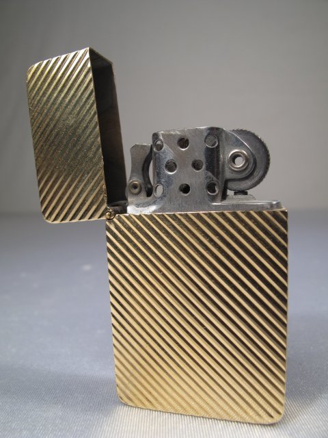 ZIPPO LIGHTER w/ 18 KT GOLD CASE 20.5 dwt: Lighter with 18 kt yellow gold case and Zippo mechanism. Case stamped on base, 18kt together with an illegible diamond shaped hallmark. Case weight without inner mechanism 20.5 dwt. Monogram on front 