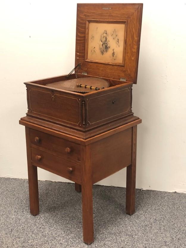 ANTIQUE REGINA POLYPHON MUSIC BOX DISC PLAYER: Antique Regina polyphon single comb music box with stand. Plays 15 1/2" discs, includes 21 discs. The music box itself measures 12" tall x 22.1" wide and 20" deep. Stand measures 26.5" tall x 23" wide