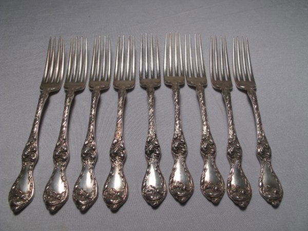 NINE HEAVY REPOUSSE STERLING SILVER FORKS c1900: Nine heavily repoussed American sterling silver forks made by Reed and Barton with a patent date of May 22, 1900. Floral lily motif. Each spoon is 7" in length. Total weight: 1 lb or 0.45 kg. Conditio