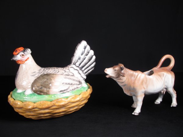 STAFFORDSHIRE POTTERY HEN DISH & AN EARLY COW CREA: Antique Staffordshire pottery serving dish in the form of a hen sitting on a nest sold together with an Early 20th Century porcelain cow creamer. Dish: 7" tall by 9" wide by 7" wide. Creamer: 7 1/2" i