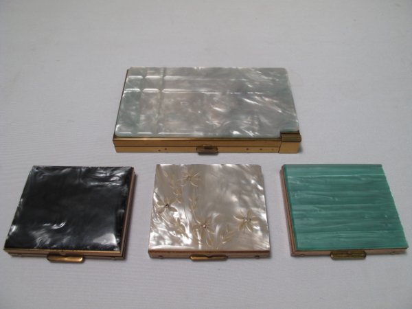 FOUR ASSORTED FAUX MOTHER OF PEARL COMPACTS: First is a large rectangular Volupte compact with engraved design on the grey celluloid lid. Interior is in good condition, exterior is also in good condition. Measures 3" by 5 1/4". Second is an unma