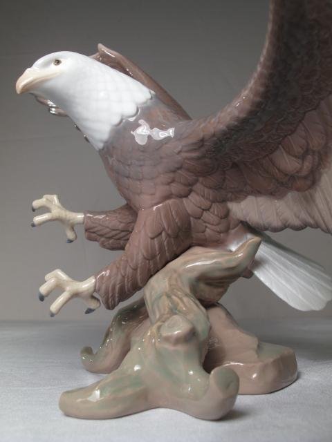 LLADRO FIGURINE AMERICAN EAGLE #6476 BOXED STAND: Lladro porcelain figurine of a bald eagle. Model #6476. Title: "A Symbol of Pride". Height: 12" including stand. Width (wing span): 17". Weight including stand: 4.0 lbs. Condition: Good with original 