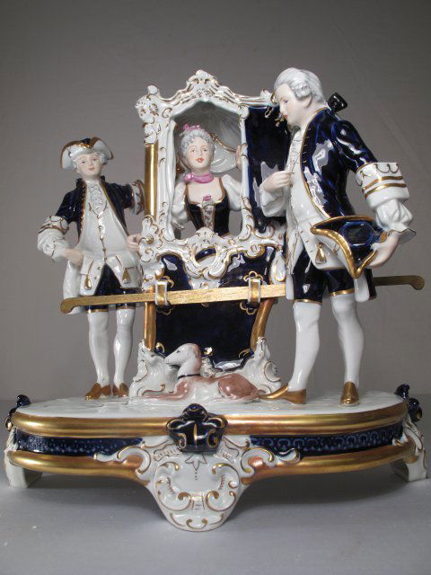 LG CZECH PORCELAIN FIGURINE LADY SEDAN CHAIR: Hand painted Czechoslovakian figurine comprising two men in Eighteenth Century costume talking to a lady in a sedan chair. Second half of the 20th Century. Decorated with cobalt blue and gold gilding.