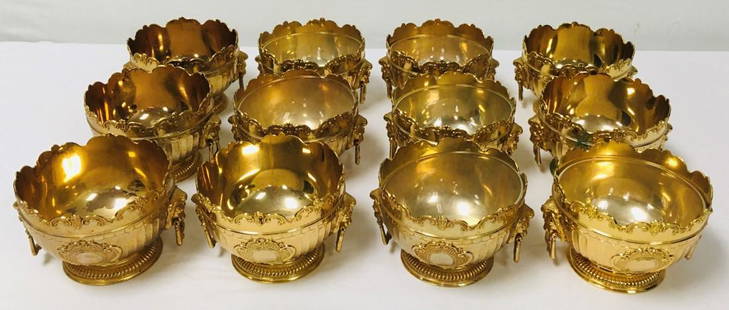 CORBELL & CO GOLD PLATED MONTEITH STYLE BOWLS 12 P: Lot of twelve Corbell & Co gold plated Monteith style bowls with glass inserts. Each one marked on base, with lions head handles on either side. Each bowl measures a total of 5.75" wide x 3.75" tall.