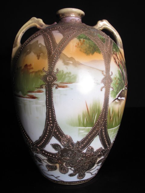NIPPON MORIAGE PAINTED LANDSCAPE TWO HANDLED VASE: Nippon hand painted porcelain landscape vase with two handles and gilt Moriage style decorations. Early 20th Century. Height: 7 1/2". Width at widest point: 5 1/2". Condition: good with minor wear.