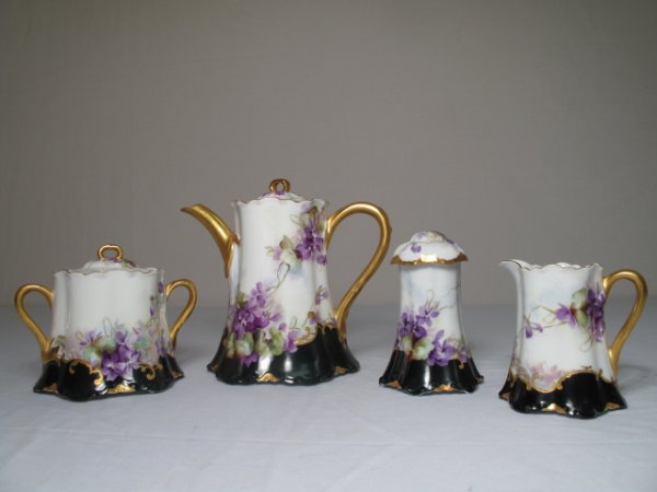 ANTIQUE FOUR PIECE LIMOGES TEA SET GILDED VIOLETS: Antique four piece Limoges, France porcelain tea set circa 1890. Each piece is decorated with hand painted violets and gilded trim. Largest piece is the tea pot which is 7" tall and 7 1/2" wide from b