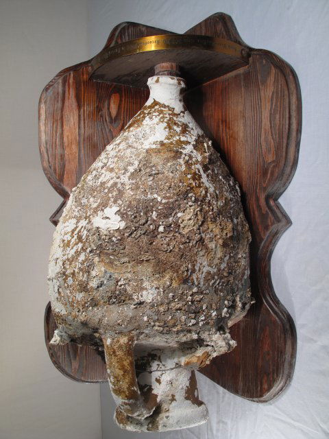 CIRCA 300 AD PARTIAL GREEK WINE AMPHORA ON STAND: Circa 300 AD partial Greek wine amphora mounted on a wood corner shelf. Metal engraved label reads, "Greek wine amphora, circa 300 AD. Recovered 1966 in Turkey while diving". Height of partial amphora
