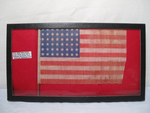 CASED G.A.R STARS AND STRIPES REUNION FLAG: Cased Stars and Stripes American flag, reportedly from the 50th Gettysburg reunion of 1913. Flag has 48 stars. Width of flag: 9 1/4". Height of flag including stick: 7". Padded case measures 14 1/2" x