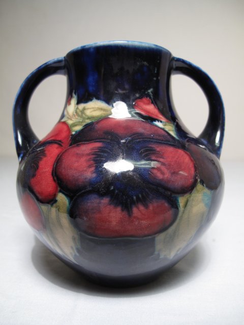 WILLIAM MOORCROFT BLUE GROUND HANDLED POPPY VASE: William Moorcroft blue ground two-handled poppy vase. Mid 20th Century. Green painted script signature. Impressed marks. Height: 5". Width at widest point: 4 3/4". Weight: 1.2 lbs. Condition: good wit
