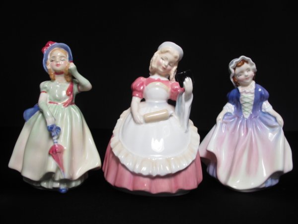 THREE ROYAL DOULTON FIGURES OF GIRLS IN DRESSES: Three Royal Doulton porcelain figurines of girls. Figures are entitled, "Babie", "Dinkey Do" and "Cookie". Tallest figurine is 5". Widest is 3 1/2" at widest point. Total weight: 1.1 lbs. Condition: g