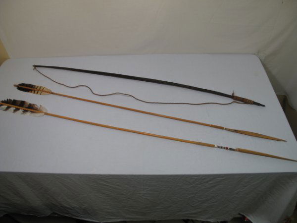 TRIBAL BOW WITH TWO ARROWS: A tribal long bow along with two bamboo shafted arrows. Origin unknown. 20th Century. Longest arrow is 69" in length. Total weight: 2.3 lbs. Condition: Generally good. Minor wear and material loss.