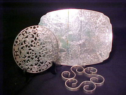 STERLING SILVER OVERLAY TRIVET + OTHERS: STERLING SILVER OVERLAY TRIVET + OTHERS Marked sterling silver overlay trivet measures 6" wide. Some discoloration on reverse. Oval silver plated extension trivet measures 11" long by 8 1/4" wide.