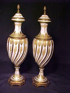 PAIR FRENCH PORCELAIN GILT PAINTED URNS: PAIR FRENCH PORCELAIN GILT PAINTED URNS Bronze mounted handpainted urns measuring 16 1/2" tall by 4 1/2" wide.