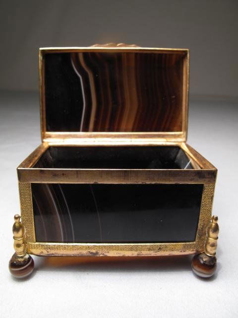 ANTIQUE BRONZE MOUNTED POLISHED AGATE CASKET: Antique bronze mounted polished agate casket on four agate ball feet. Mid 19th Century European. Height: 1 3/4". Width: 2 1/2". Weight: 0.2 lbs. Condition: some wear to the original gilding on the bro