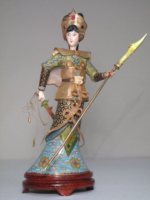 CHINESE CLOISONNE & IVORY FIGURE: FEMALE WARRIOR: A Chinese figure depicting a female warrior. Body is cloisonne, hands, head, belt buckle and epaulets are ivory. Gilt metal collar, headdress, vest and spear. Cloisonne spear. Condition good but for s