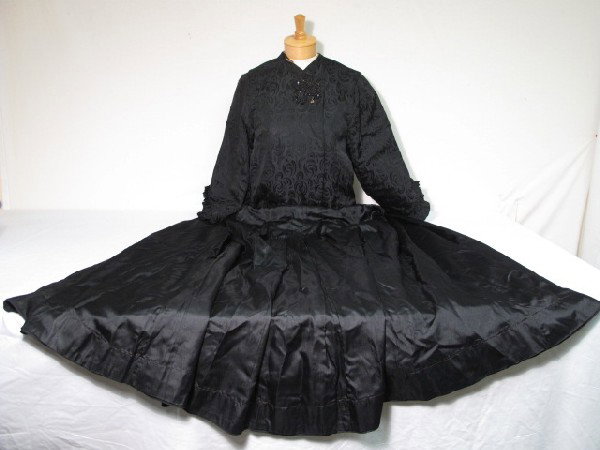 VINTAGE BLACK BROCADE JACKET SKIRT 2 PCS C 1880: Vintage black brocade jacket, skirt 2 pieces, circa 1880. Jacket is ruffled along bottom of sleeves. Beaded closure. Rips, tears, fraying. 25 inches from neck to bottom. 14 inch sleeves. Skirt is plea
