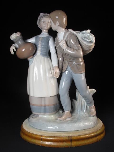 LLADRO PORCELAIN FIGURINE MAN AND WOMAN: Lladro porcelain figurine of a man carrying a basket on his back and a woman with a jug with flowers in it. Painted and glazed porcelain. Stamped "Lladro" on bottom. Good condition, no damage. Comes w