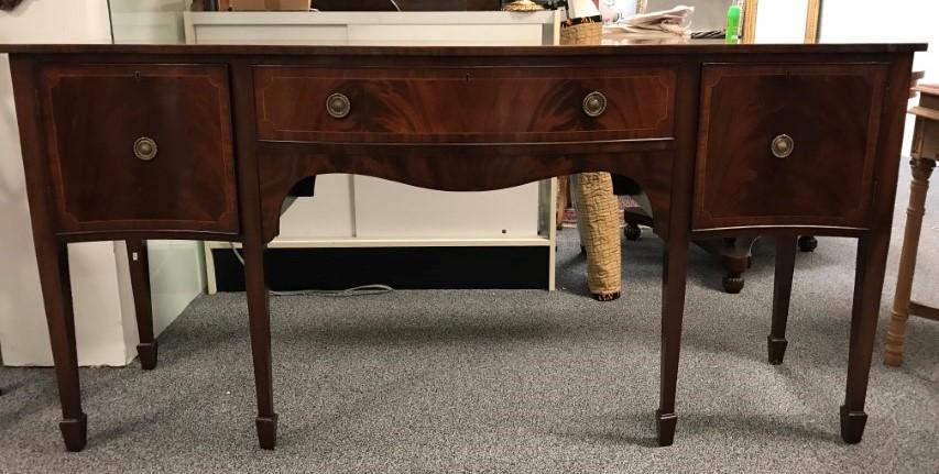 AMERICAN HEPPLEWHITE STYLE MAHOGANY SIDEBOARD: AMERICAN HEPPLEWHITE STYLE MAHOGANY SIDEBOARD. Later 20th c. possibly Robert Irwin; SERPENTINE FRONT figured mahogany with satin wood string inlay; raised on tapered legs with spade feet; 2 doors (wit