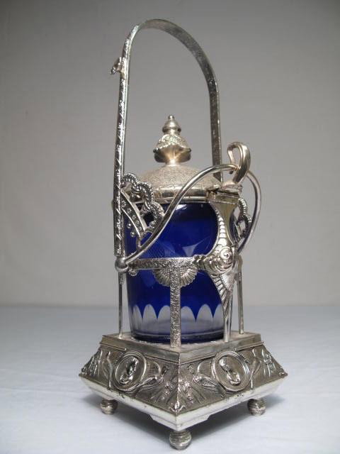VICTORIAN SILVER PLATE & COBALT PICKLER CASTOR: Victorian silver plate pickle castor. Cobalt cut glass jar. Lid lifts off cup when handle is tilted back. Good condition, minor tarnishing, see images. Measures 12.5" tall x 4.5" wide. Shipping weight