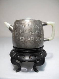 EARLY CHINESE PEWTER & JADE TEAPOT: Early Chinese pewter teapot. Engraved with symbols and characters on sides and bottom. Jade handle, jade lid handle, and jade spout. See images. On wooden stand. Some discoloration/ markings from age.