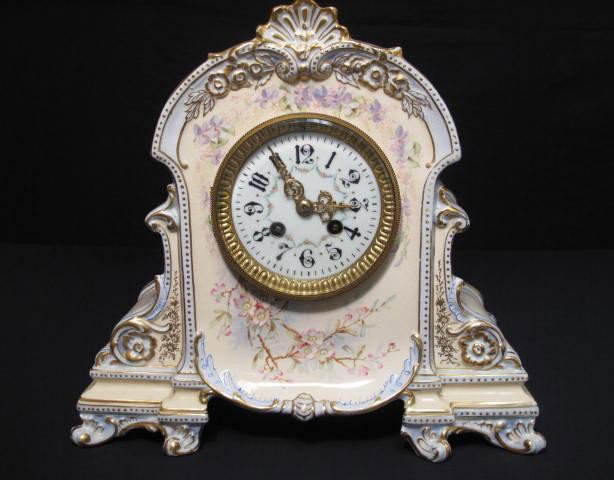 JAPY FRERES ROYAL BONN PORCELAIN MANTLE CLOCK: A Royal Bonn floral decorated porcelain mantle clock with Japy Freres, France time and strike 8 day mechanism, enameled dial and fancy gilt filigree hands. Measures 12" tall by 13" wide and 5" deep. S