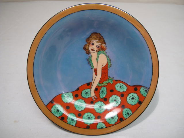NORITAKE ART DECO TAZZA: FLORAL DRESS: Unusual Noritake tazza. Blue ground, amber rim, luster finish with hand painted design of a young girl in a floral dress in the Art Deco manner. Measures 6.5" wide and 2 3/4" tall. Shipping weight .8 