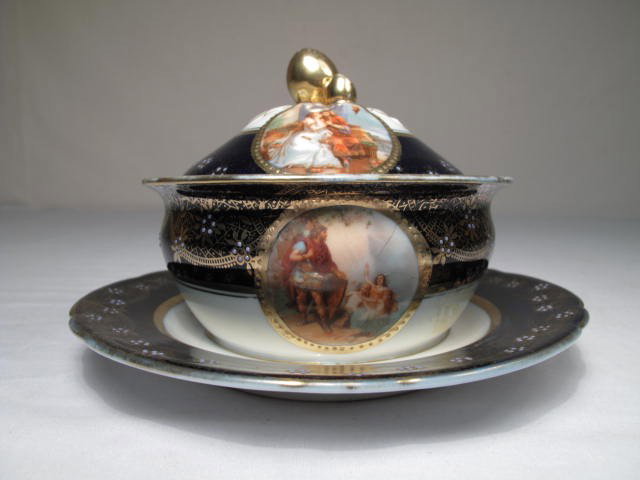 ACKERMANN & FRITZE PORCELAIN COVERED DISH: Ackermann & Fritze covered dish. Cobalt blue and gilt coloring. Two miniature scenes on lid, and two on side of dish depicting romantic scenes. Marked on underside of lid, and on very bottom of plate 